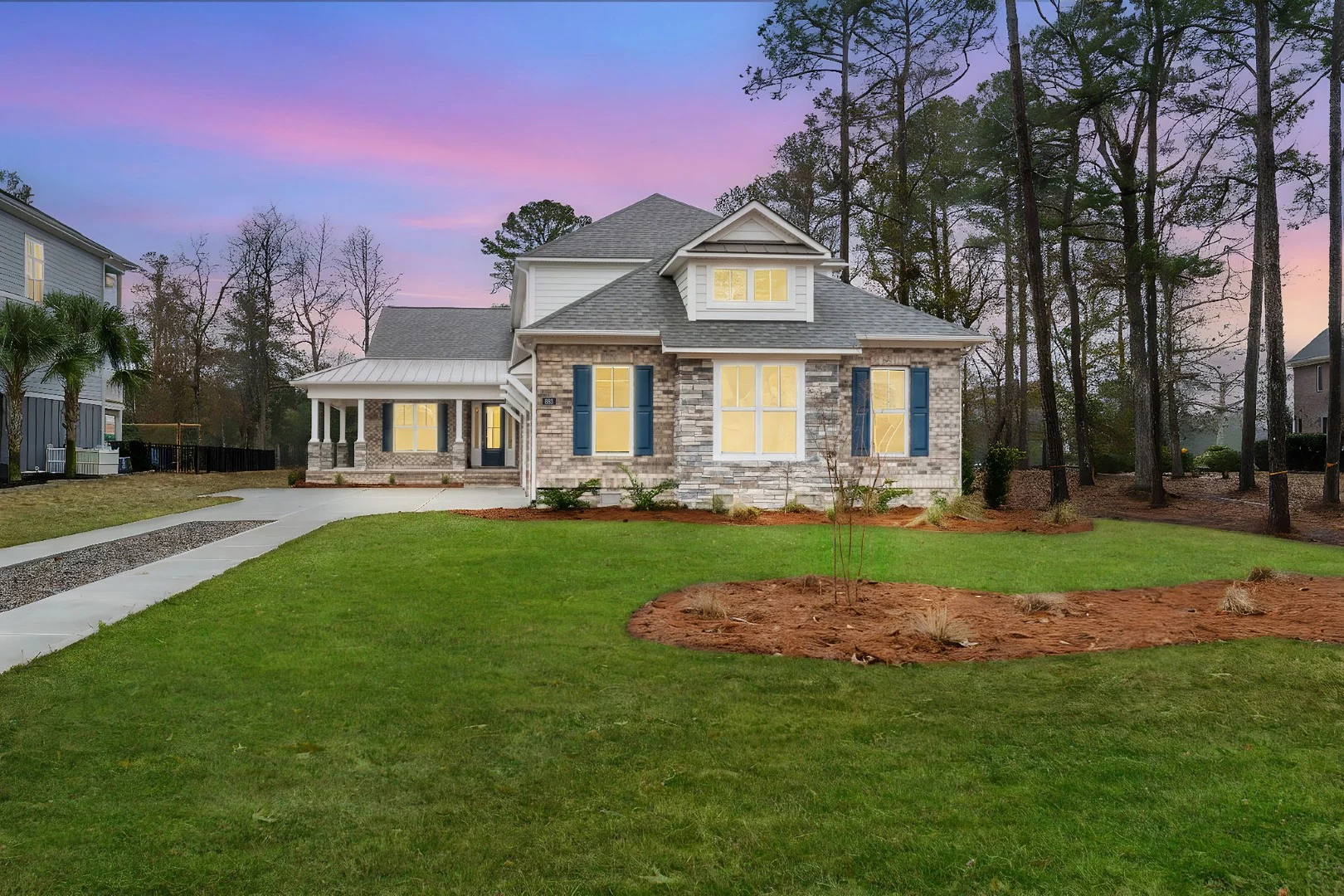Modern two-story home with brick facade, surrounded by trees at sunset. A prime example of quality home builder craftsmanship.